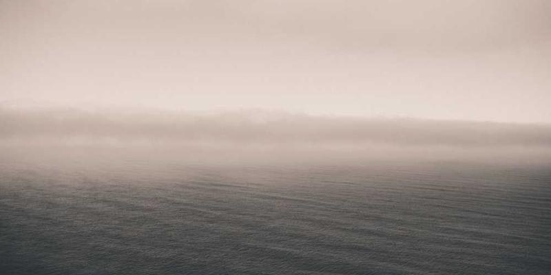 说明：一位女性在厨房的角落里，灯光昏暗，她专注地按照颜色和大小将洗好的碗盘整齐地放入橱柜中，背景是温暖的灯光和厨房的温馨氛围。